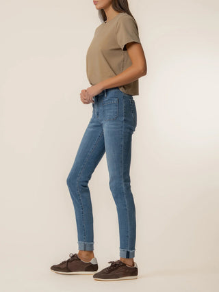 Person wearing blue jeans and a beige shirt on a plain background