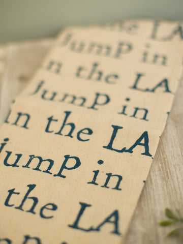 a beige cotton hand towel reading jump in the lake
