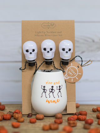 a white stemless wine glass that reads rise and wine with dancing skeletons printed across perfect for halloween decor gifts