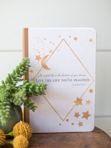 a journal with copper stars moon and a henry david thoreau quote on its satin cover