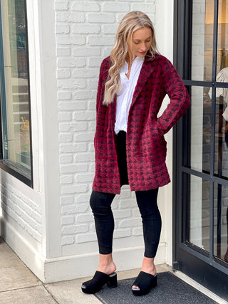 a dark red and black houndstooth jacket with an above the knee hem perfect for proper london vibes shown with black leggings