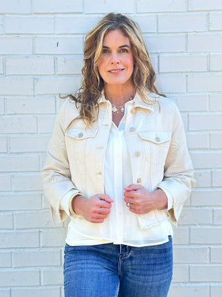 a cream ecru denim jacket with delicate flower details and a fray