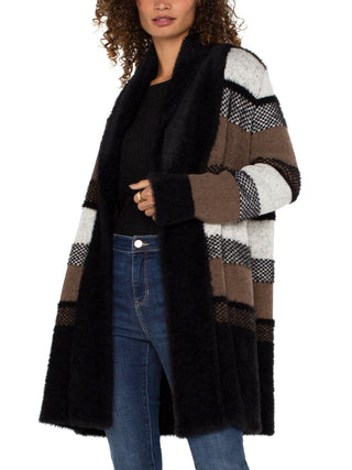 a soft faux fur cardigan in a striped black and tan design with cozy pockets