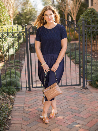 two piece navy layered knit sweater and midi length pleated skirt paired with natural sandals