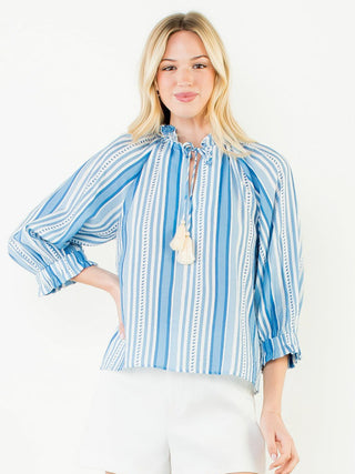 a beachy blue striped blouse with ruffles and a tassel tie at the neck