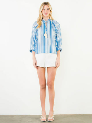 a beachy blue striped blouse with ruffles and a tassel tie at the neck paired with white shorts