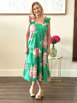 a bright green tiered maxi dress with a pink floral print and ruffled straps worn with tan heels