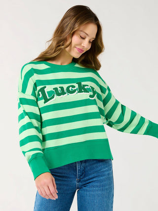a st pattys day green striped sweater with the word lucky on the front paired with jeans