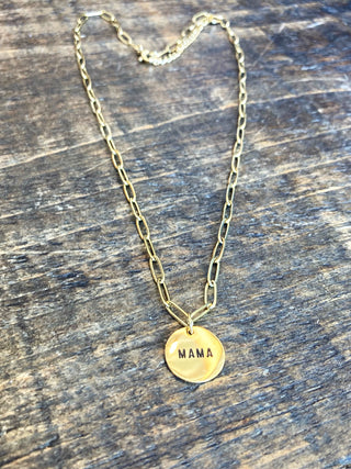 a gold chain link necklace with a round pendant that reads Mama