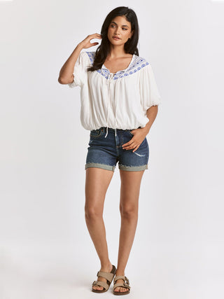 relaxed white self tie v neck blouse with blue embroidery detail worn with blue jean shorts