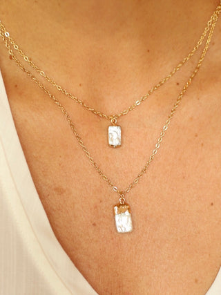 a layered necklace with two gold chains and rectangular pearl charms perfect for everyday wear