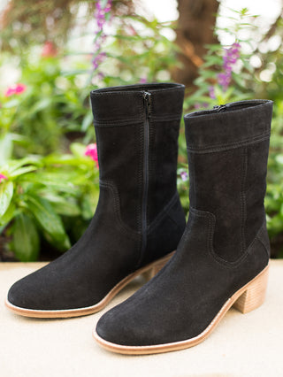 a pair of black mid calf boots in black suede with a tan leather sole perfect for fall and winter fashion