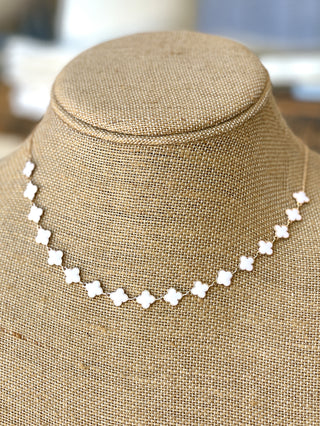 bright gold chain necklace with a delicate mini white resin quatrefoil design