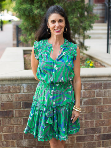 a tropical dress in shades of green with ruffles and a v neckline in an above the knee cut