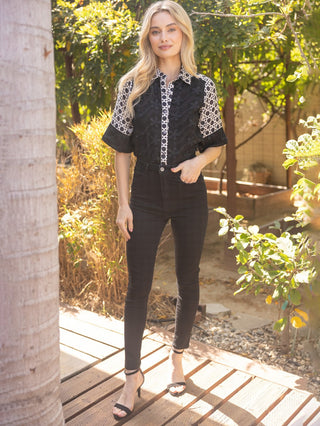 a fun and unique black and white patterned button up blouse worn with black pants