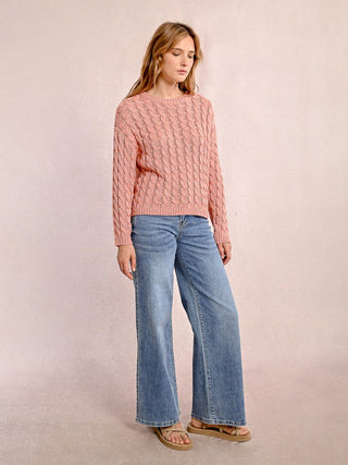 a classic peachy pink cable knit sweater with a subtle metallic finish worn with light denim jeans