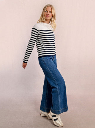 a lightweight off white and navy striped sweater with subtle gold accents worn with dark blue jeans