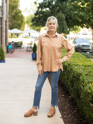 a tan button down shirt in suede with long sleeves and large pockets perfect for fall fashion shown with denim pants