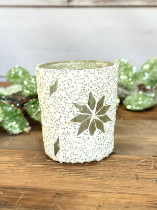 a white mosaic votive snowflake candle that illuminates warm light