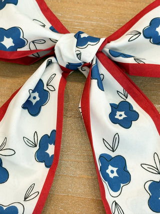 white scarf with blue floral patterns and red edges 