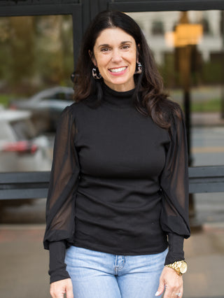 a black mock turtleneck with see through balloon statement sleeves great for any capsule wardrobe