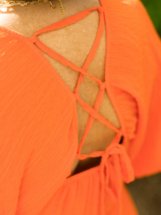 an orange above the knee dress with short puff sleeves and an open back tie in soft textured fabric