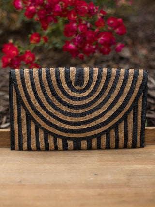 a straw clutch bag with black and tan print lining and a magnetic snap closure
