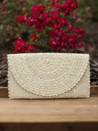 a straw clutch bag in ivory rattan with a magnetic snap closure