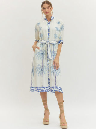a breezy coastal blue and white palm tree patterned midi dress with a front tie worn with tan sandals