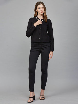 a black long sleeve button up cardigan with sparkling pearl and rhinestone accents worn with black pants
