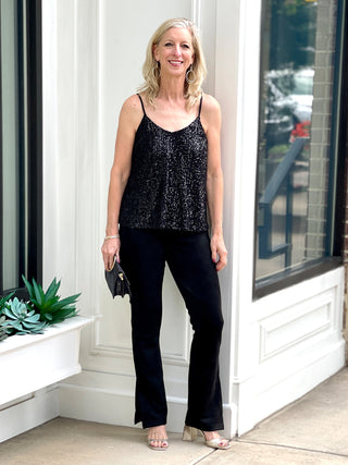 a slinky black sequin and glitter spaghetti strap top perfect for holiday parties and new years eve shown with black pants
