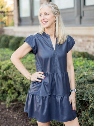 a dark blue faux leather tiered dress with puff cap sleeves and an above the knee hem perfect for casual chic dressing