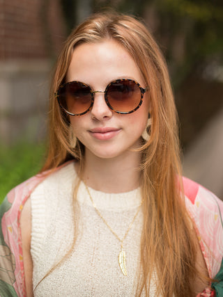 round vintage shape sunglasses in a tortoise shell pattern on a smiling woman
