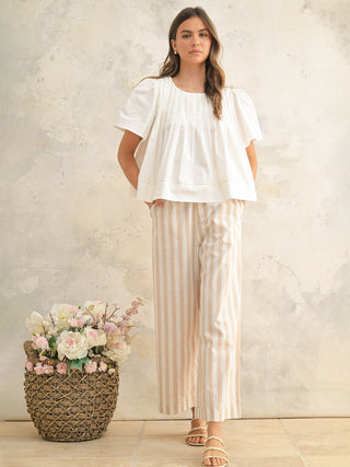 a flowy oversized pleated white short sleeve blouse worn with beige and white pants