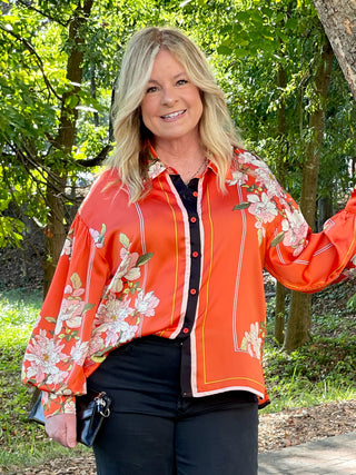 a relaxed fit orange button down top with long sleeves and flower details and stripes in slinky fabric