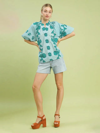 a bright teal puff sleeve top with a fun floral pattern paired with jean shorts