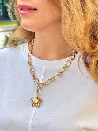 a gold puffy star shaped pendant on a gold chain necklace