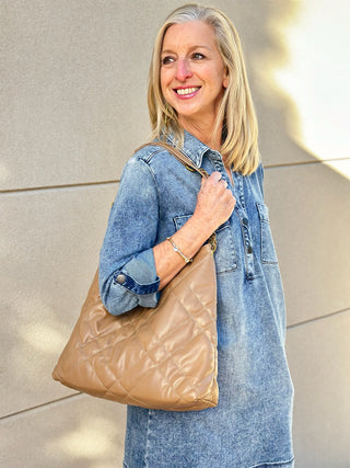 a beige and tan quilted vegan leather purse with gold hardware worn with a denim dress