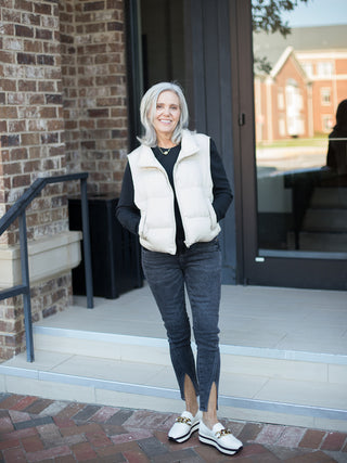 a white puffer vest perfect for layering in fall and winter shown with a black long sleeve top