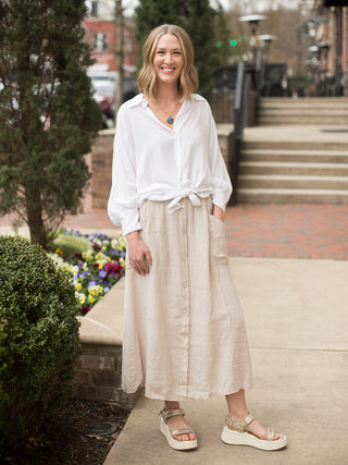 silky white button up shirt with long dolman sleeves worn with midi length khaki linen skirt