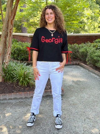 a black and red georgia game day top with dainty red ribbons on the sleeves worn with white jeans