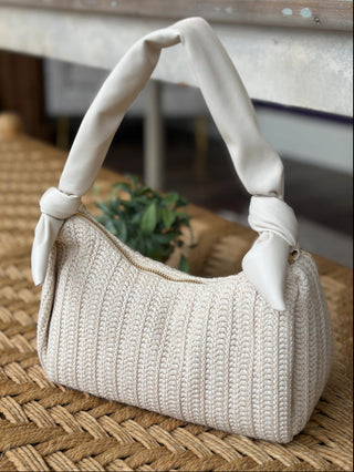 an ivory stitched handbag with a cute tied handle