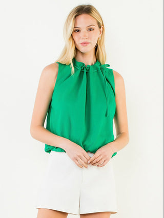Woman wearing a green sleeveless blouse with a tie neckline on a white background