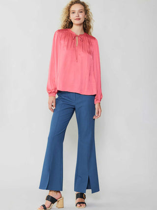 delicate bright pink split neck blouse with long puffed sleeves worn with blue flared pants