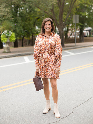 an orange printed long sleeve dress in lightweight fabric with an above the knee hemline shown with white boots