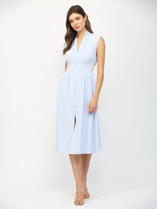 a coastal blue striped sleeveless midi dress with a front v neck zip and cinched waist worn with white sandals