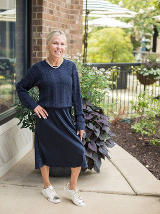 a navy cable knit sweater in crop style with long sleeves perfect for layering shown with midi navy skirt