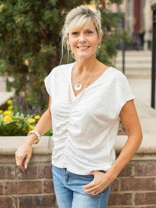 a white cotton top with a v neckline and short sleeves shown with denim shorts