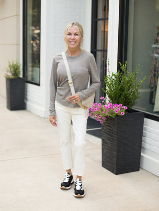 a light grey long sleeve top with ruching on the side and a crew neckline great for summer to fall shown with white pants