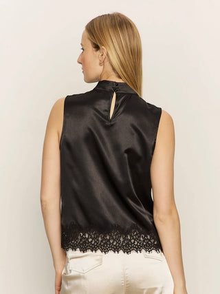 a black satin sleeveless mock tank with a lace hem worn with white pants